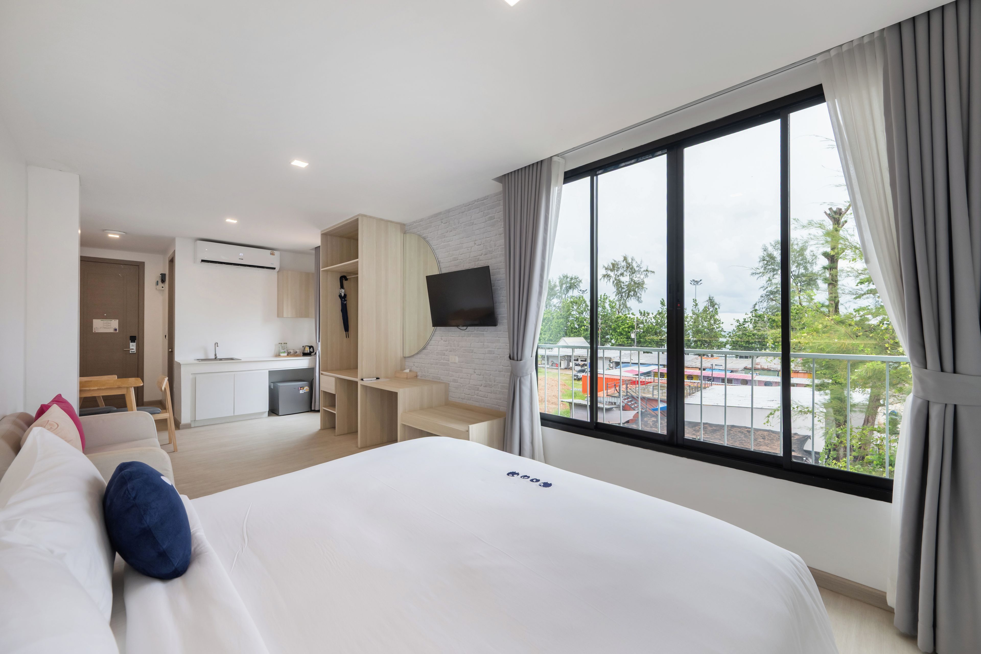 A hotel room with a bed, a desk, a TV, and a balcony with a view.