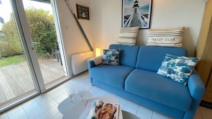 A blue sofa with patterned cushions, a magazine on a white table, and a framed picture of a lighthouse on the wall. - CALLEA II - Holiday home with garden in Carnac - K16 (Carnac)