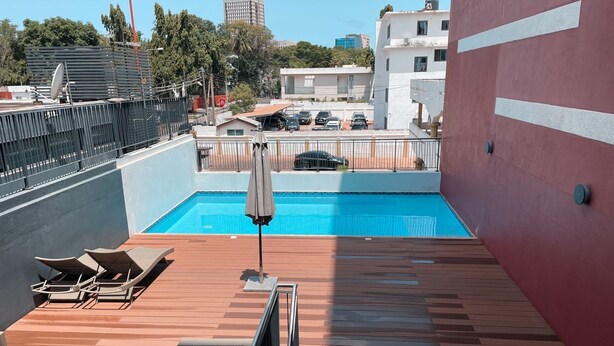 A rooftop pool area with lounge chairs, a pool, and a view of the cityscape. - Beaufort Ridge (Accra)