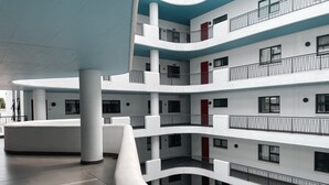 A multi-story building with a curved balcony, white walls, and multiple balconies with railings. - Beaufort Ridge (Accra)