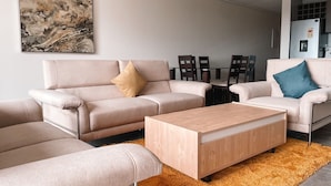 A modern living room with a beige sofa, a wooden coffee table, and a large abstract painting on the wall. - Beaufort Ridge (Accra)