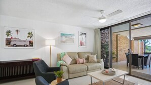 Uma sala de estar moderna com sofá, poltronas, mesa de centro e um espaço de refeições com mesa e cadeiras.