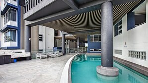 Un área de piscina interior moderna con un diseño curvo, asientos junto a la piscina y un paseo techado.