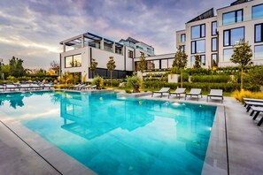 A modern hotel with a swimming pool, lounge chairs, and a well-maintained garden. - Therma Numera Longevity SPA (Burgas)
