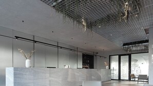 A modern lobby with a reception desk, seating area, and a ceiling with hanging plants. - Therma Numera Longevity SPA (Burgas)