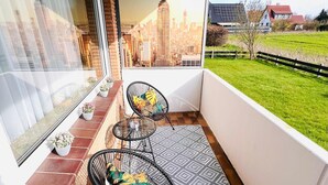Un balcón con vista panorámica de la ciudad, dos sillas, una mesita y un tapete estampado.