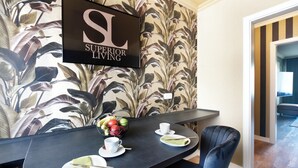 Un comedor con una mesa negra, platos blancos y un cuenco de fruta. Una silla negra se encuentra colocada junto a la mesa.