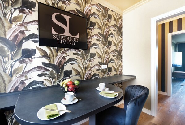 A dining area with a black table, white plates, and a bowl of fruit. A black chair is positioned at the table.