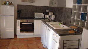 Una cocina compacta equipada con refrigerador, microondas, horno y pileta.