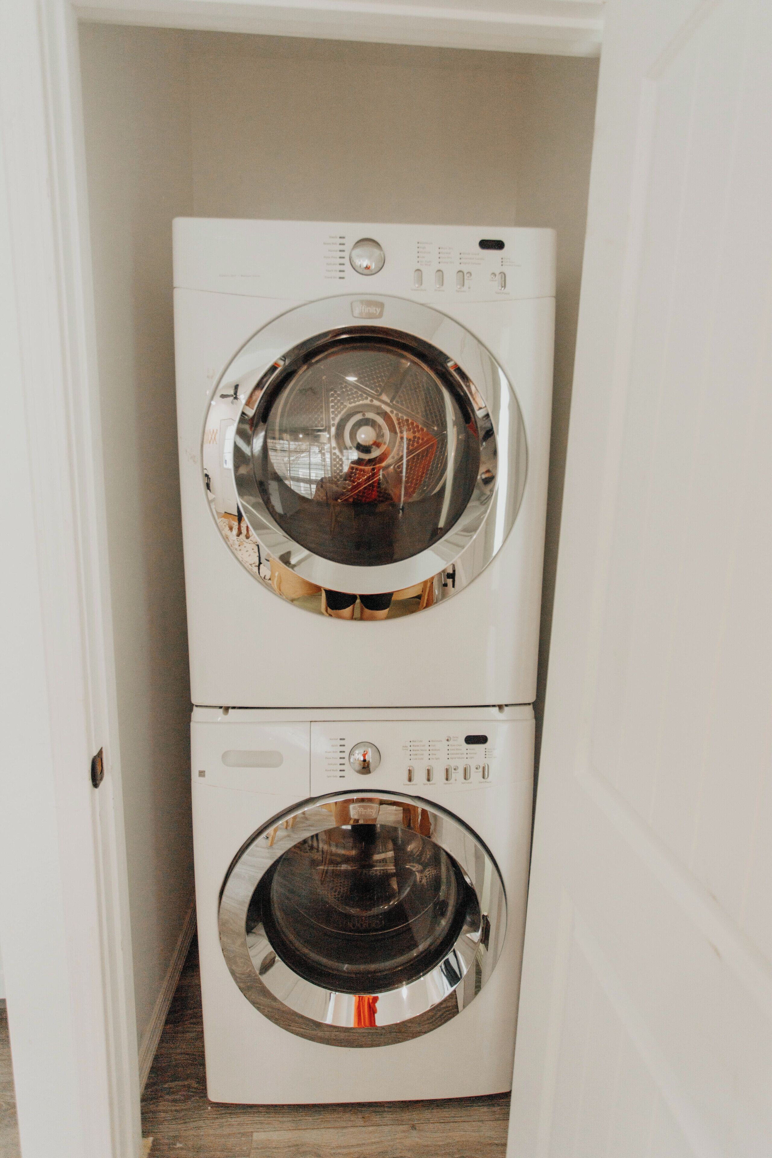 Een compacte, witte wasmachine en droger gestapeld in een smalle gang.