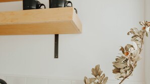 A kitchen counter with a clear glass vase containing a dried plant, a soap dispenser, and a black faucet.