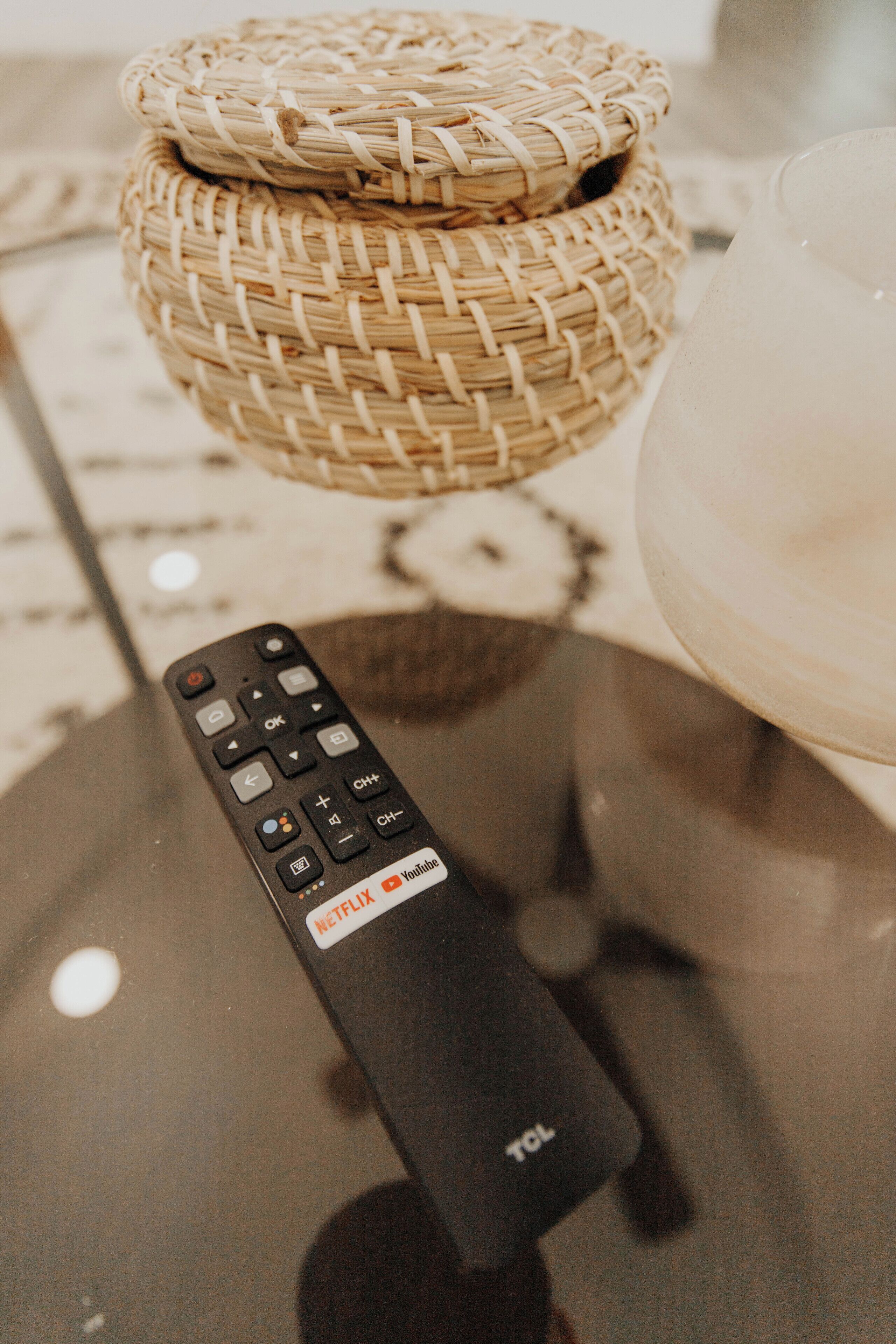 Une télécommande ornée d’un autocollant Netflix, posée sur une table en verre.