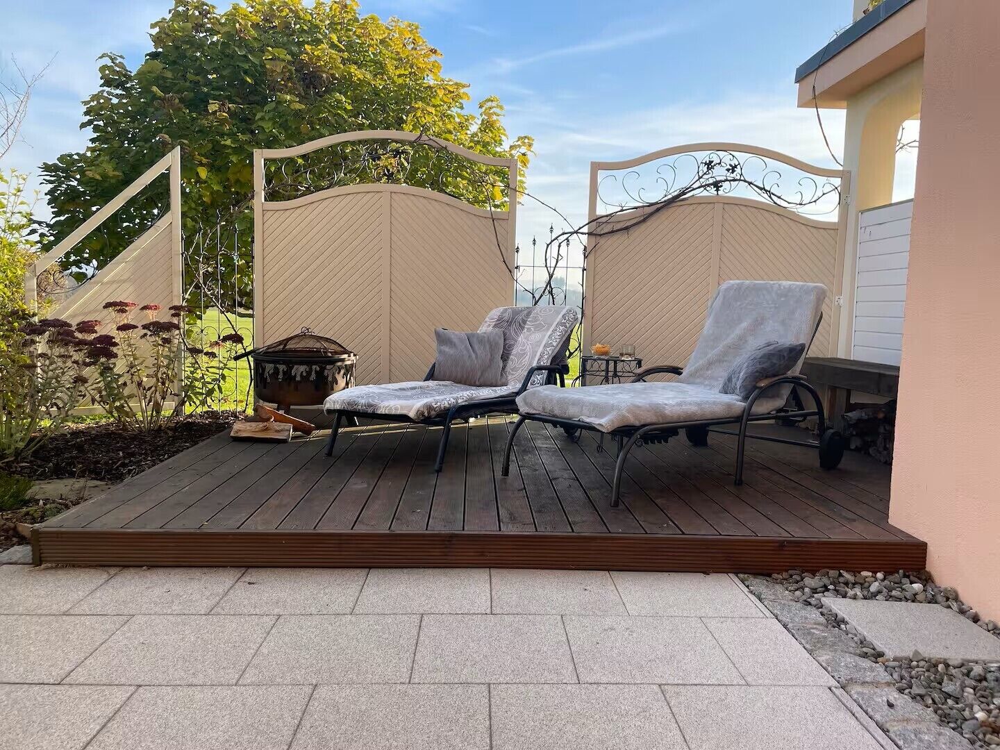 Eine Terrasse mit zwei Liegestühlen, einem dekorativen Blumentopf und einem kleinen Tisch.