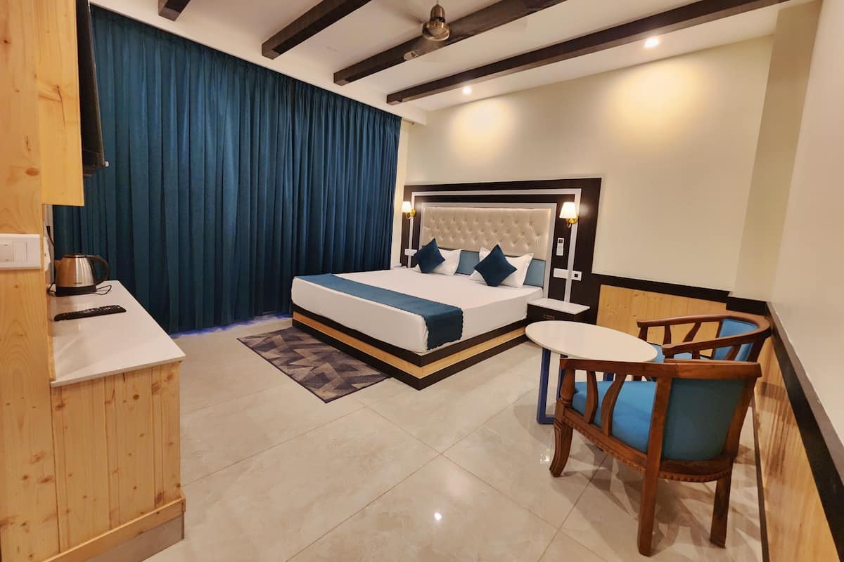 Ein Hotelzimmer mit Bett, Nachttisch, Sessel und kleinem Tisch mit Stuhl.
