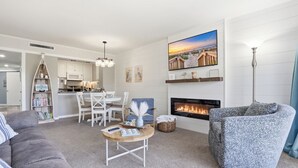 Una sala de estar moderna con chimenea, un sofá, una silla, un comedor y una cocina.