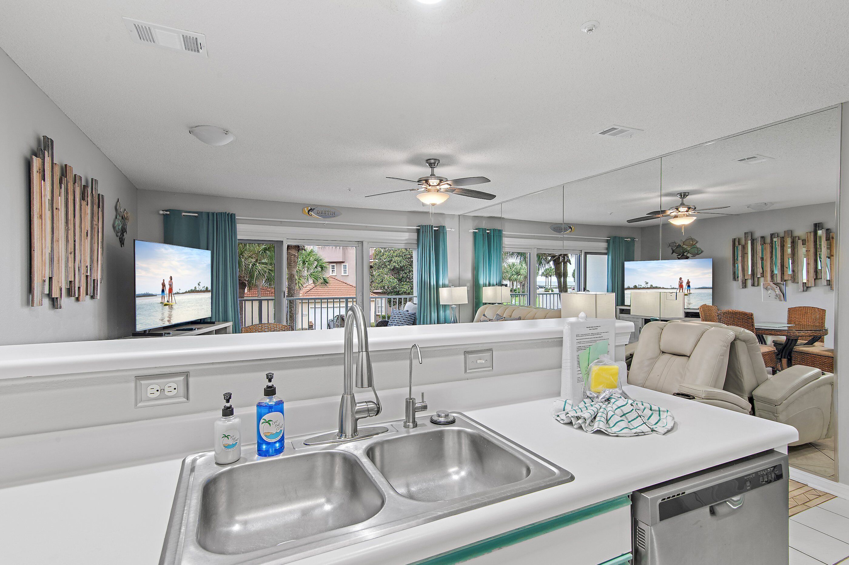 A modern kitchen with a double sink, a dishwasher, and a large window offering a view of the outdoors.