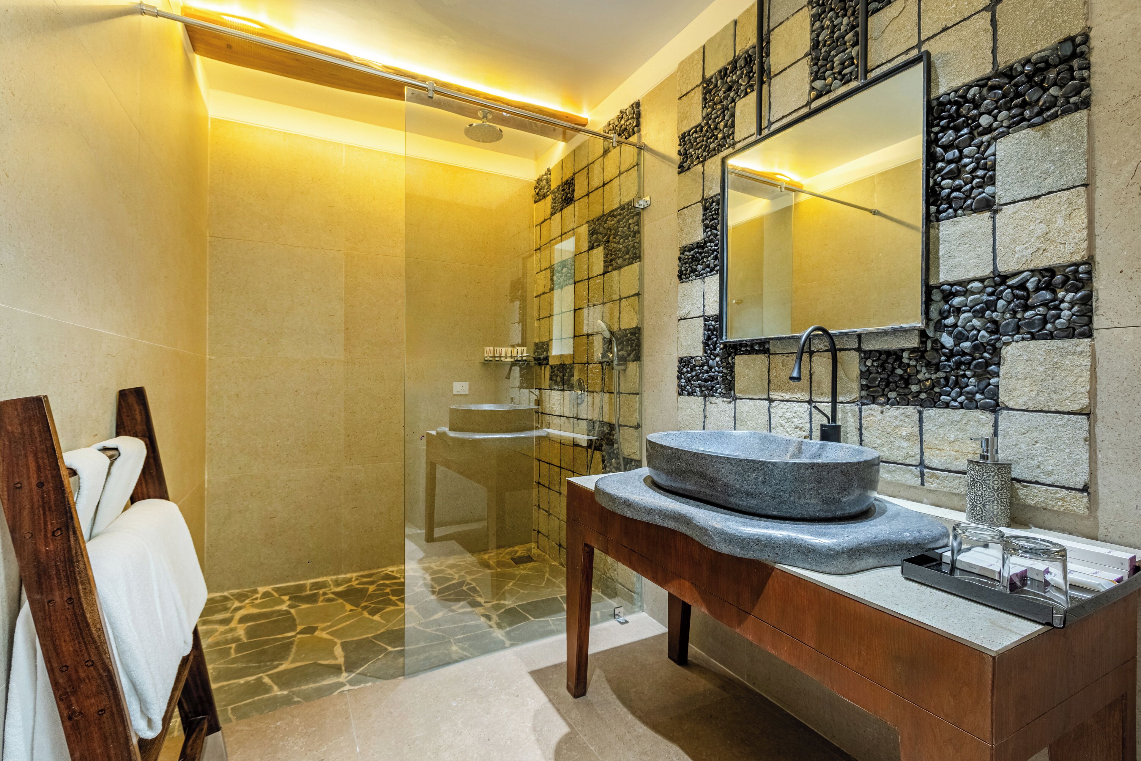 A modern bathroom with a stone sink, a glass shower enclosure, and a wooden vanity.