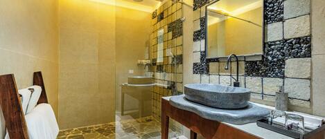 A modern bathroom with a stone sink, a glass shower enclosure, and a wooden vanity.