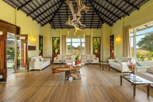 Un salón espacioso con techo alto, suelo de madera y dos sofás blancos. Una original mesa de centro hecha de un tronco de árbol se encuentra en el centro.