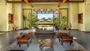 A spacious lobby with a high ceiling, a central bench, and a large window offering a view of the outdoors. - Sterling Tipeshwar (Kelapur)