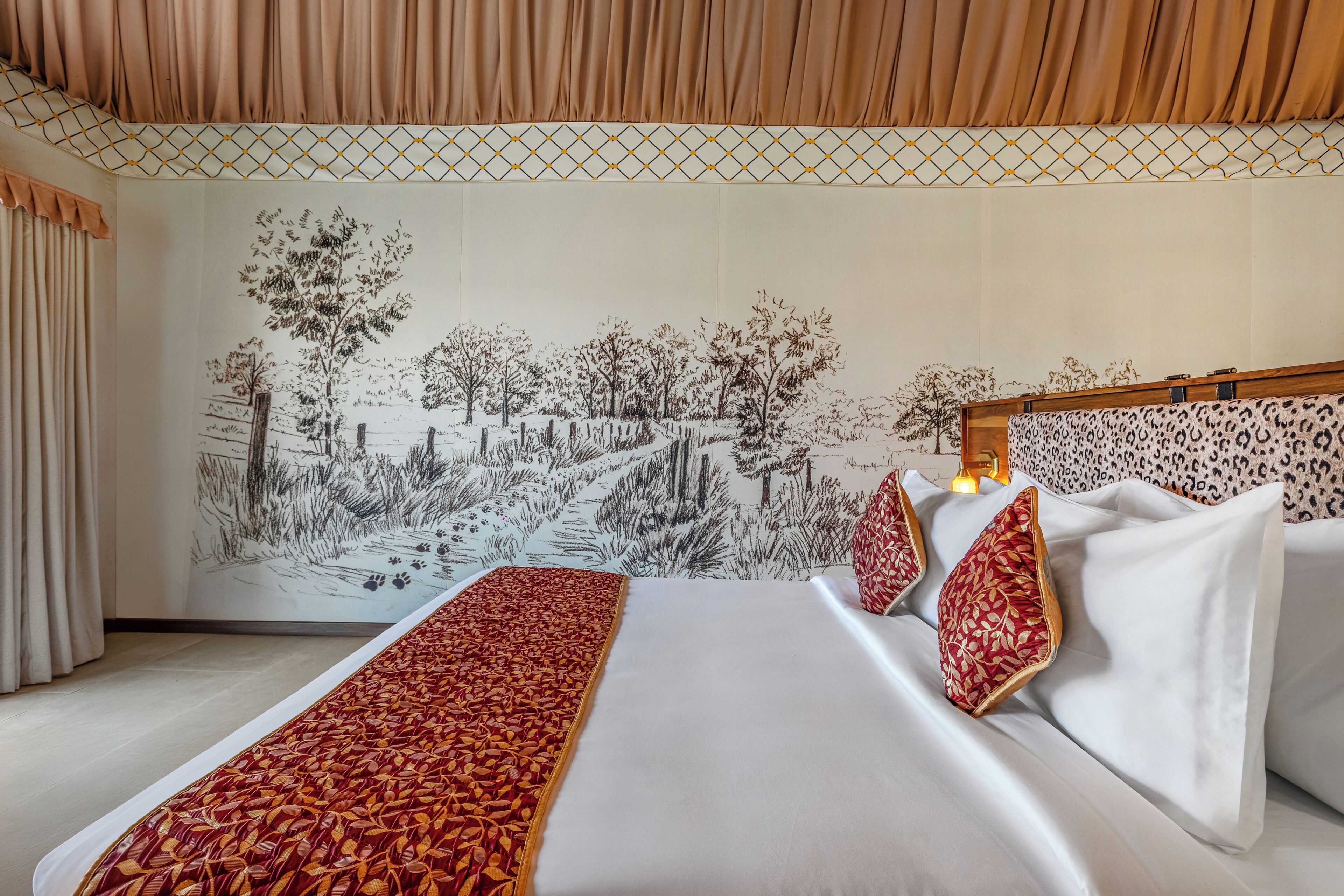 Una habitación de hotel con una cama grande, una manta estampada y un mural de un paisaje en la pared.