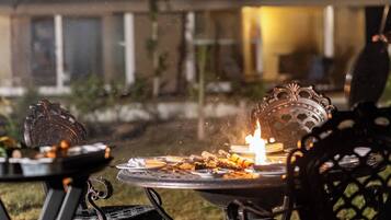 Un espace extérieur aménagé pour les repas, avec un barbecue et des chaises.