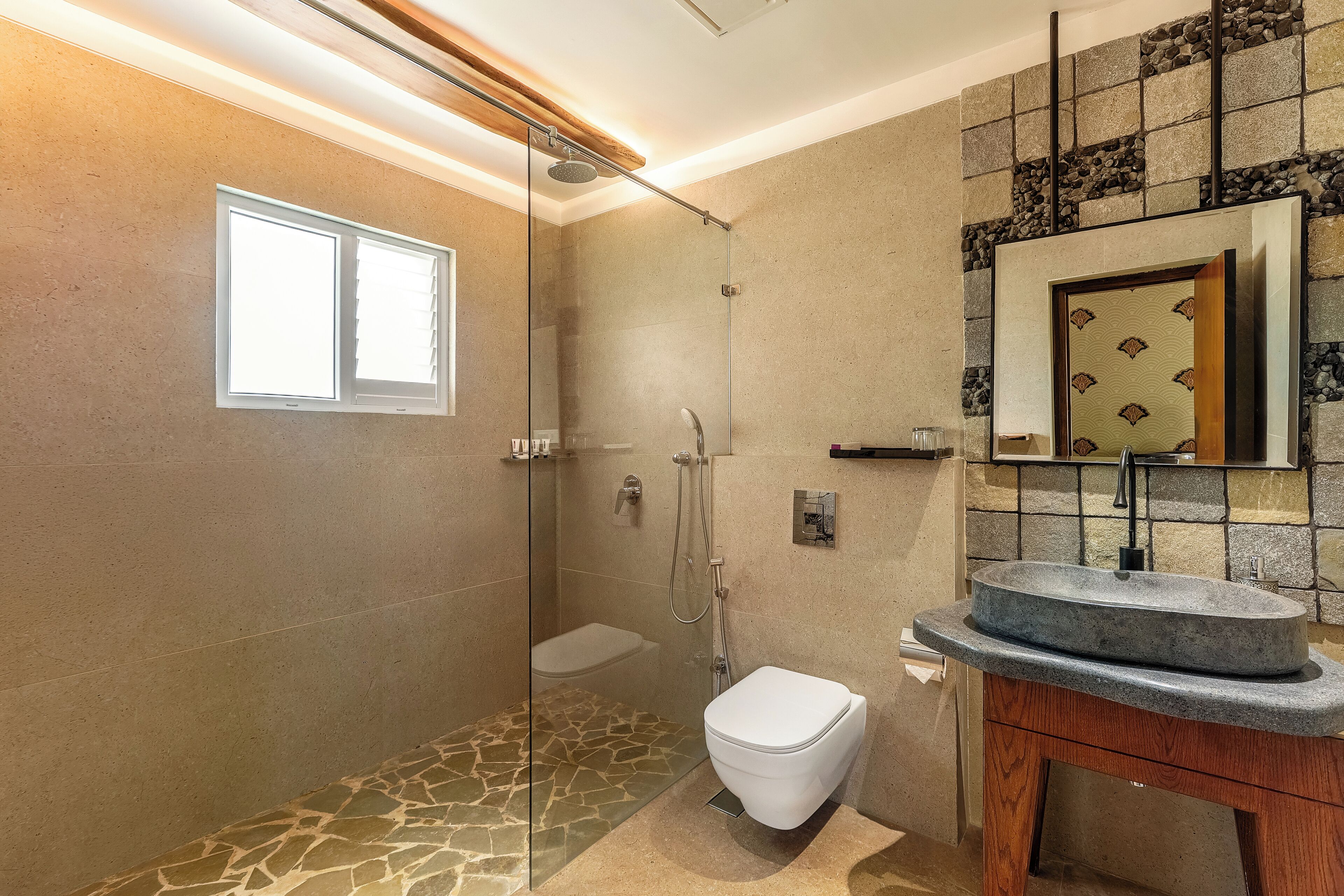 Un bagno moderno con doccia vetrata, un WC bianco e un pavimento in pietra.