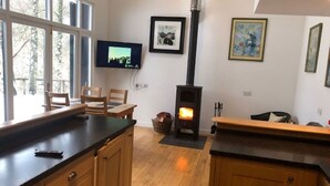 A modern kitchen with wooden cabinets, a black countertop, a built-in stove, and a television mounted on the wall. - Beautiful private villa for 4 people with WIFI, TV, terrace and pets allowed (Inverness)