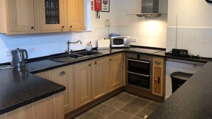 A compact kitchen with wooden cabinets, a built-in oven, a microwave, and a sink. - Beautiful private villa for 4 people with WIFI, TV, terrace and pets allowed (Inverness)