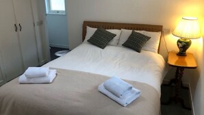 A neatly made bed with two folded white towels, a wooden headboard, and a bedside lamp. - Beautiful private villa for 4 people with WIFI, TV, terrace and pets allowed (Inverness)