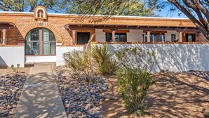 A modern building with a brick facade, a large arched window, and a small garden with rocks and desert plants. - Elegant Green Valley Villa 55+ (Green Valley)