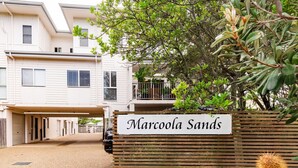 A residential building with a sign reading "Marcola Sands" and a wooden fence with a cactus. - Marcoola Sands Retreat Steps from Marcoola Beach (Marcoola)