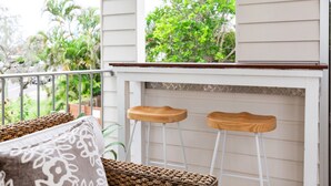 A balcony with two wooden stools, a woven basket, and a patterned cushion. - Marcoola Sands Retreat Steps from Marcoola Beach (Marcoola)