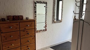 A room with a wooden dresser, a mirror with a stone frame, and a coat rack.