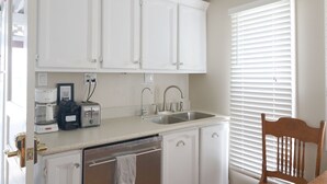 A kitchen with white cabinets, a sink, a toaster, and a window with blinds. - 28 Morris - Classic, centrally located cottage in Chautauqua Institution! (Chautauqua)