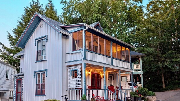 A two-story house with a porch, a bicycle, and potted plants. - 28 Morris - Classic, centrally located cottage in Chautauqua Institution! (Chautauqua)
