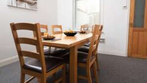 A dining area with a wooden table and chairs, a bowl of fruit, and a painting on the wall. - Hampton House Spacious Accommodation In Stockton (Stockton-on-tees)