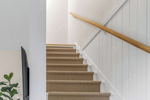 Eine Treppe mit hölzernem Geländer und beige gefärbten Teppichstufen.