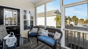 A sunroom with wicker furniture, large windows, and a view of the neighborhood. - 4 bedroom 3 bath home in Cherry Grove. Screened porch Firepit. 2 blocks to ocean (North Myrtle Beach)