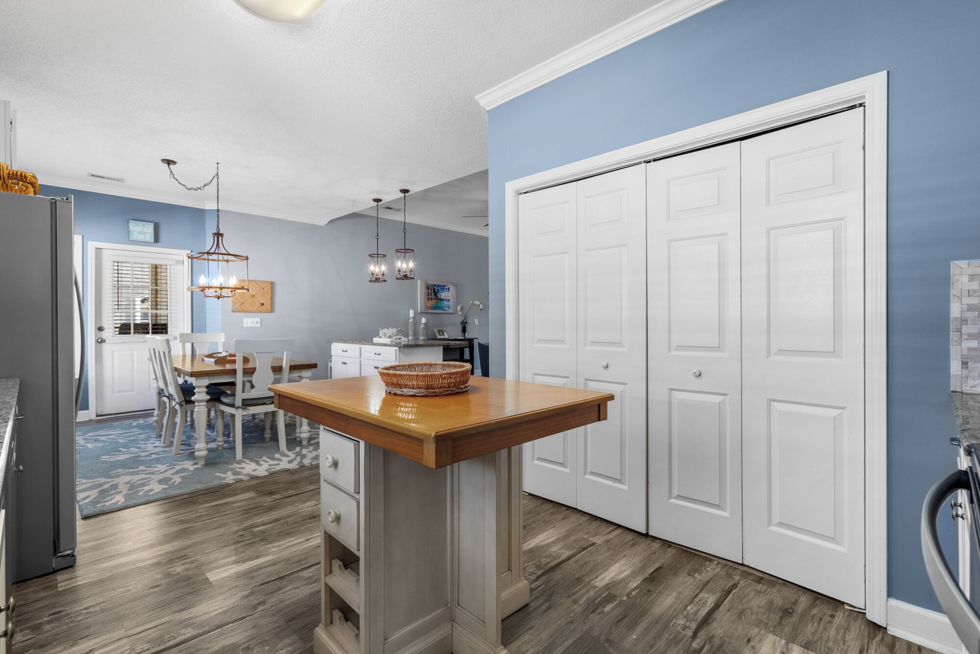 A modern kitchen with a wooden island, white cabinets, and a blue accent wall.