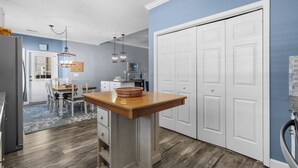 A modern kitchen with a wooden island, white cabinets, and a blue accent wall. - 4 bedroom 3 bath home in Cherry Grove. Screened porch Firepit. 2 blocks to ocean (North Myrtle Beach)
