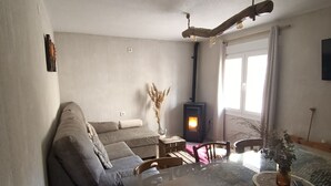 Ein Wohnzimmer mit Glastisch, einer Couch, einem Kamin und einem Esstisch mit Stühlen.