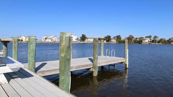 A wooden dock extending into calm water, with houses visible in the background.