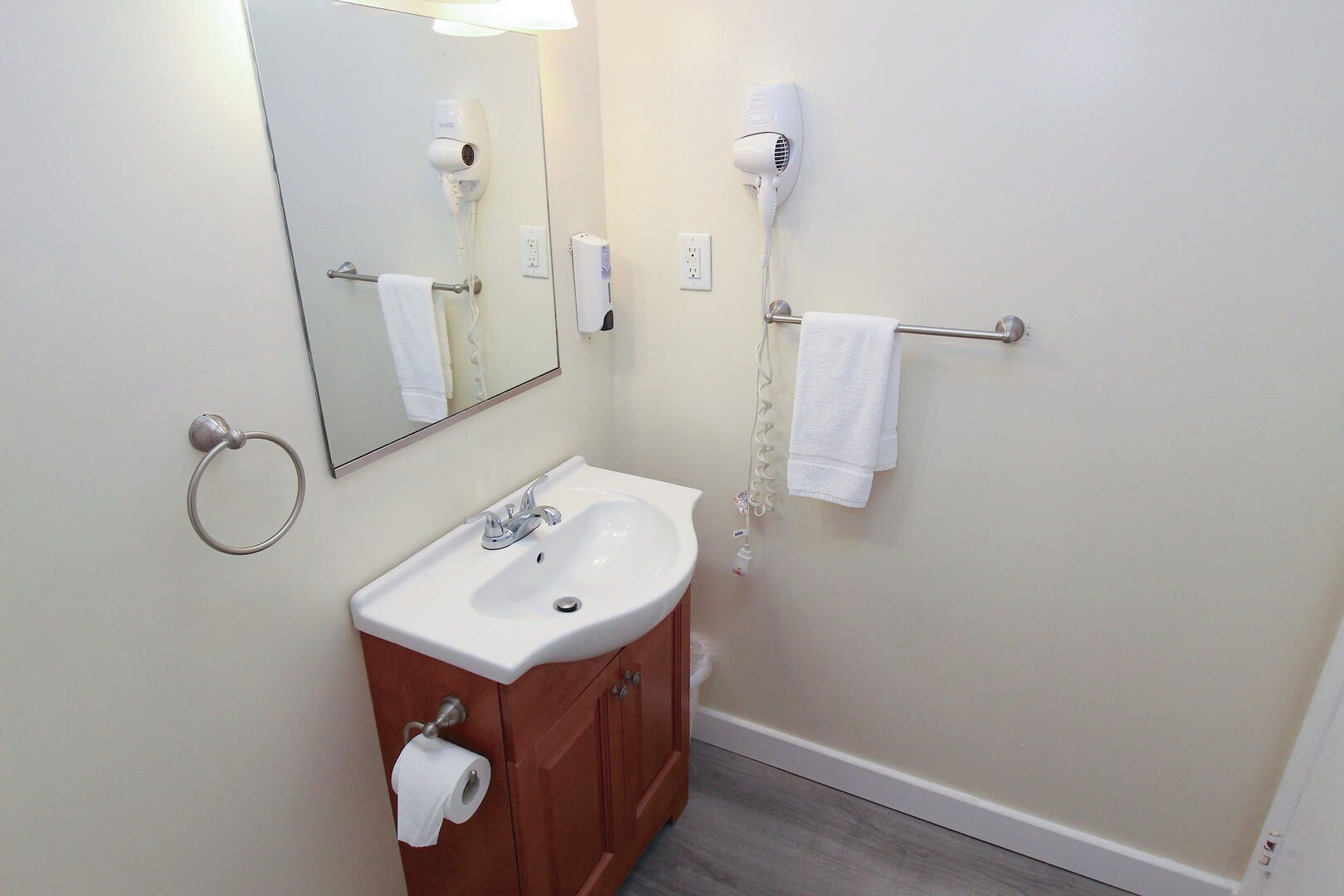 A bathroom with a sink, mirror, towel rack, and hair dryer.