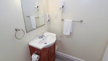 A bathroom with a sink, mirror, towel rack, and hair dryer.