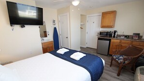 Een hotelkamer met een bed, een televisie, een kitchenette en een badkamer.