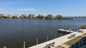 A waterfront property with a dock, benches, and houses along the shore. - Wren Watch 1 Queen Regular Fin N Feather (Nags Head)