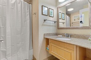 A bathroom with a shower curtain, a sink with a towel, and a mirror.