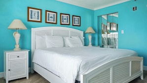 A bedroom with a white bed, two bedside tables with lamps, and a large mirror on the wall. - Rock N Reel at Villas of Hatteras Landing (Hatteras)