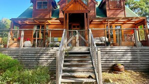 A wooden cabin with a central entrance, two side wings, and a porch with steps leading to the entrance.